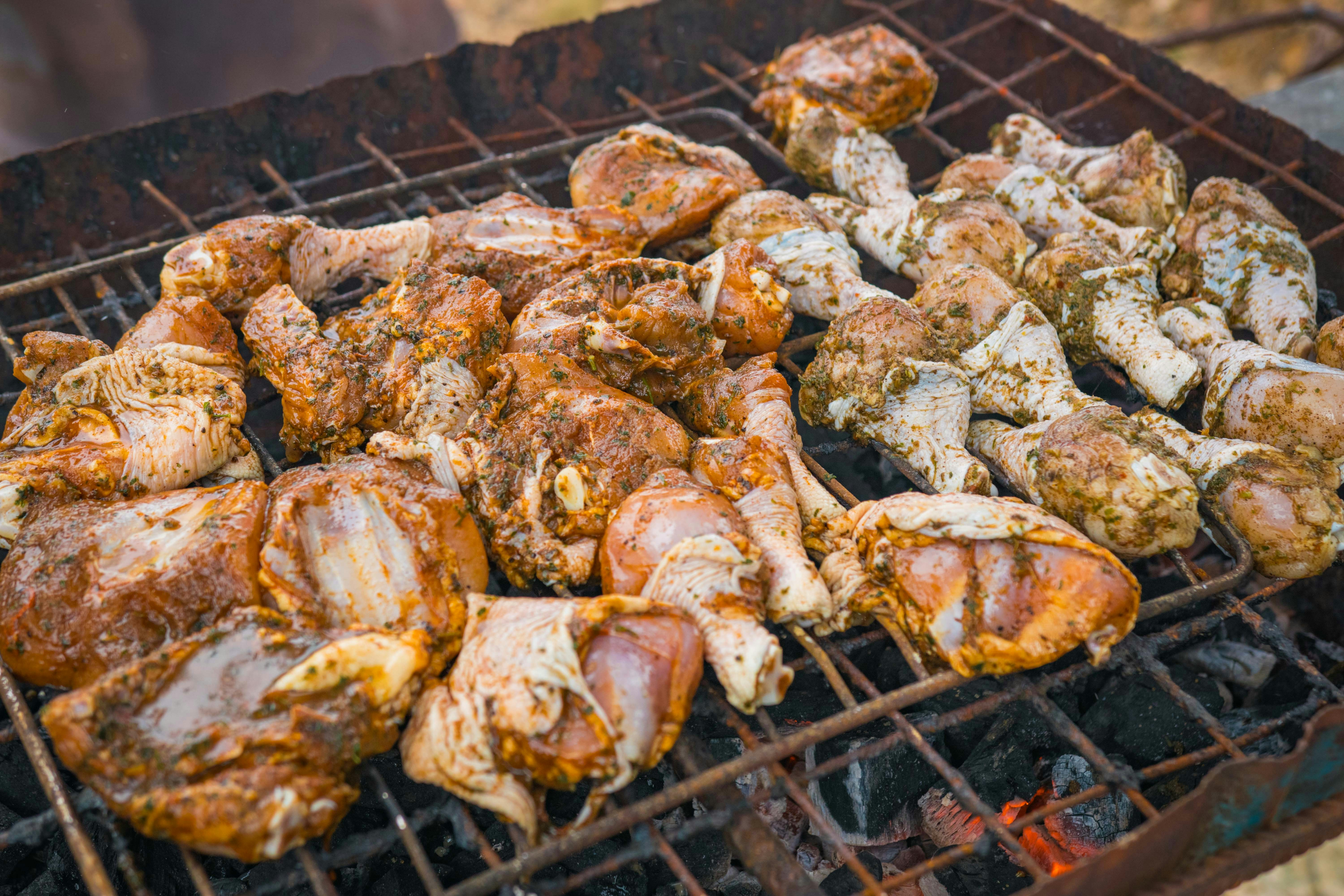Marinated chicken legs on a charcoal grill with smoke rising